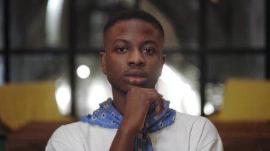 Bin yıllık ciddi bir adamın kameraya bakarken başını kaldırıp dönmesine yakından bakın. Kafede poz veren Afro-Amerikan tarzı bir adamın portresi..