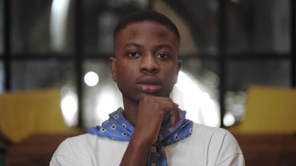 Close up view of millennial serious man propping and turning head while looking to camera. Portrait of afro american stylish guy with neckerchief posing in cafe. — Stock Video