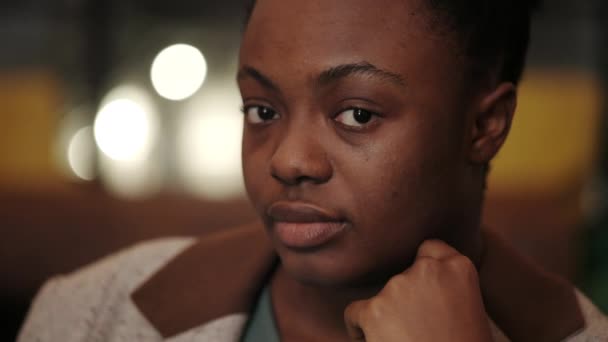 Заголовок молодої афро-американської жінки, яка нахиляється і повертається головою, дивлячись на камеру. Портрет жіночої статі. Розмите тло. — стокове відео