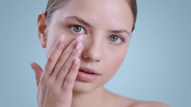 Close-up van mooie vrouw aanraken gezicht met een hand, terwijl op zoek naar camera. Portret van vrouwelijk jong model met naakt make-up poseren. Begrip kosmetologie, huidverzorging. — Stockvideo