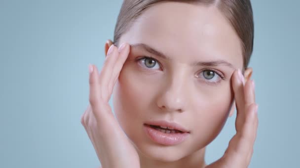 Hoofdfoto van een vrouw die haar gezicht masseert met vingers terwijl ze naar de camera kijkt. Portret van jong vrouwelijk model met naakte schouders en naakt make-up poseren. Begrip kosmetologie, huidverzorging. — Stockvideo