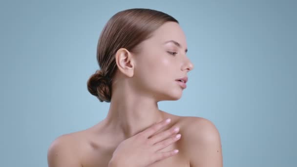 Hermosa joven tocando sus hombros desnudos y girando la cabeza. Retrato de una mujer bonita con maquillaje desnudo ligero posando en el fondo del estudio. Concepto de cosmetología, cuidado de la piel. — Vídeos de Stock