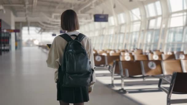 Bakåt bild av kvinna med smartphone promenader på tom flygplats — Stockvideo