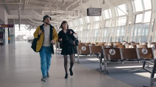 Umtriebige Menschen gehen mit Rucksäcken am leeren Flughafenterminal auf dem Weg zum Flugsteig — Stockvideo