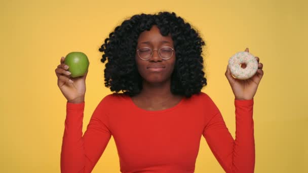 Verbaasde vrouw maakt keuze tussen appel en donut — Stockvideo