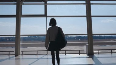 Havaalanında sırt çantalı bir kadın yürüyor.