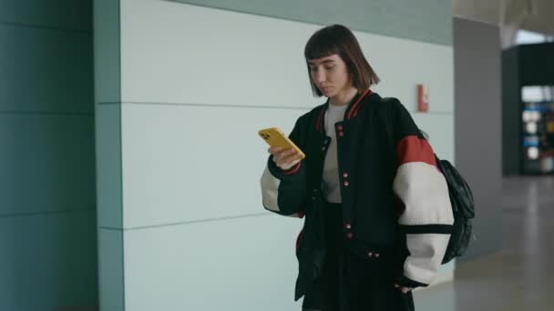 Charmante Frau benutzt Handy beim Gehen am Flughafen — Stockvideo
