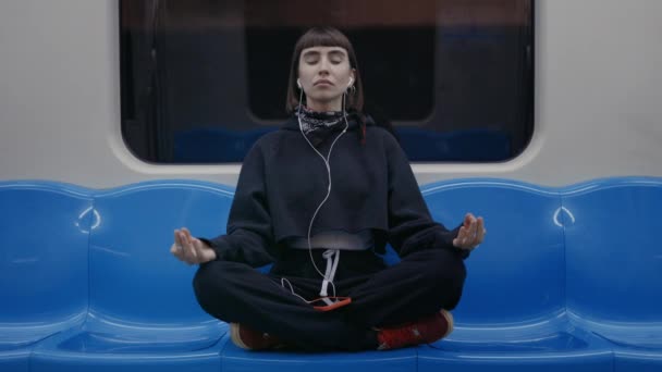 Mujer sentada en posición de loto en el metro y meditando — Vídeos de Stock