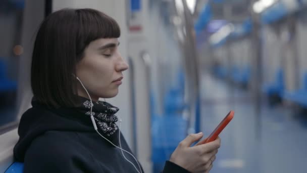 Vrouw die muziek luistert in een oortelefoon terwijl ze in de metro zit — Stockvideo