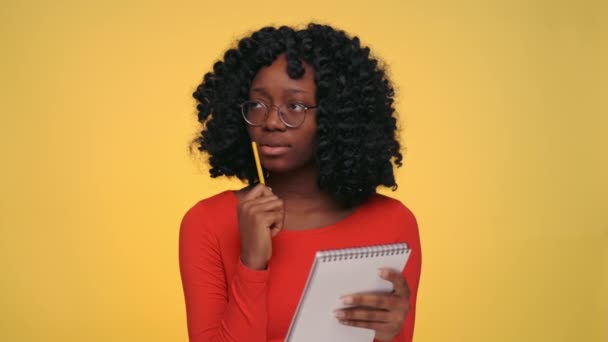 Mujer africana pensativa tomando notas de nuevas ideas — Vídeo de stock