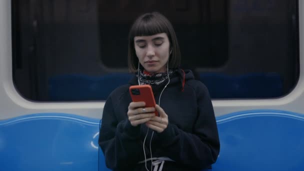 Женщина в наушниках с помощью смартфона во время поездки на метро — стоковое видео
