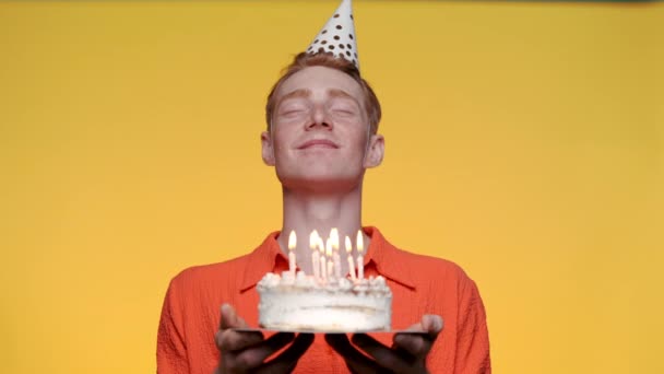 Fröhlicher Mann bläst Kerzen auf Kuchen aus und macht Wünsche — Stockvideo