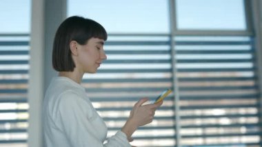 Havaalanında akıllı telefonuyla yürüyen güzel bir bayanın yan görüntüsü