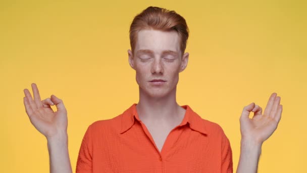 Человек, стоящий на желтом фоне и медитирующий — стоковое видео