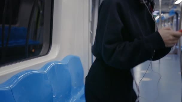 Glückliche Frau mit Kopfhörer sitzt in U-Bahn und benutzt Handy — Stockvideo
