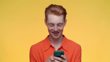 Modern akıllı telefondan mesaj yazan mutlu kızıl adam.