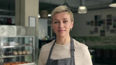 Kafeteryada duran önlüklü olgun bir kadının portresi.