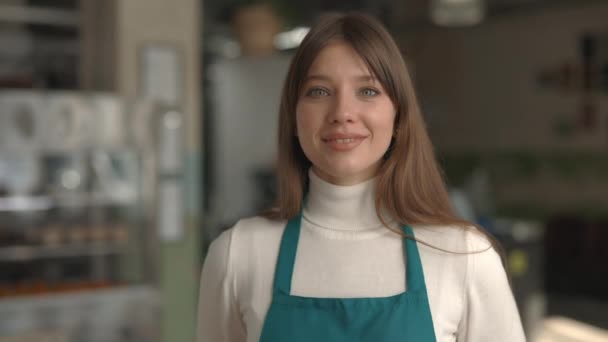 Mujer trabajadora de café en delantal sonriendo y mirando a la cámara — Vídeos de Stock