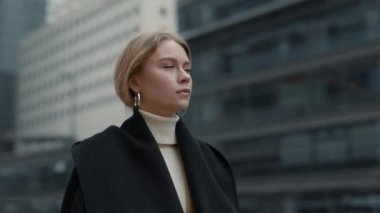Şehir caddesinde yürüyen şık siyah ceketli bir iş kadını.