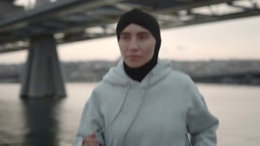 Burnunda piercing olan Müslüman bir kadın açık havada koşuyor.