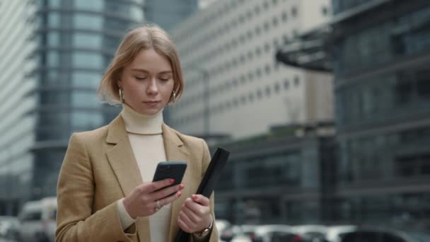Biznes pani chodzenie po ulicy z telefonu komórkowego i schowka — Wideo stockowe