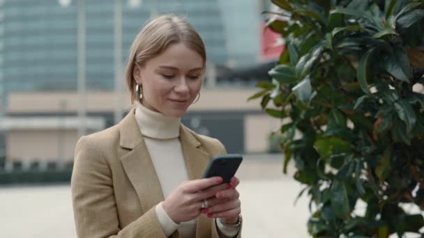 Femme caucasienne en vêtements formels en utilisant mobile en plein air — Video