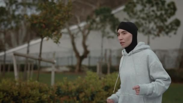 Сильна жінка в хіджабі займається спортом на міській вулиці — стокове відео