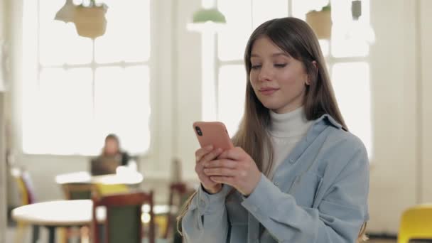 Encantadora mujer caucásica usando el teléfono celular en la cafetería — Vídeos de Stock