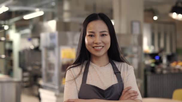 Asiática mujer sonriendo en cámara mientras posando en su propio café — Vídeos de Stock
