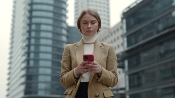 Poważna kobieta w garniturze za pomocą smartfona na ulicy — Wideo stockowe