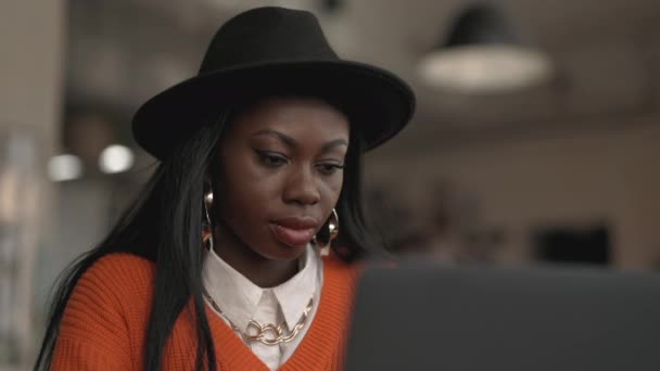 Mujer negra enfocada trabajando en el portátil en la cafetería — Vídeos de Stock