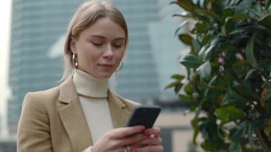 İş kadını ofis merkezinde otururken cep telefonu kullanıyor.