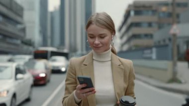 İş kadını sokakta kulaklık ve akıllı telefon kullanıyor.