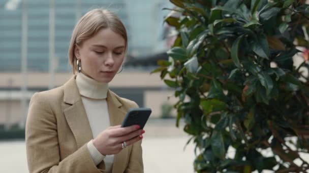 Angenehme Frau im Business-Anzug mit Smartphone auf der Straße — Stockvideo