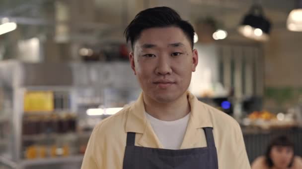 Retrato de camarero asiático amigable en delantal posando en la cafetería — Vídeos de Stock