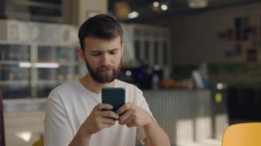 Kafe masasında otururken cep telefonunda mesaj yazan adam