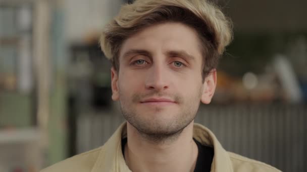 Glad ung kille med snygg frisyr poserar på lokala café — Stockvideo
