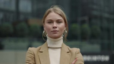 Resmi giyimli iş kadını şehir sokaklarında poz veriyor.