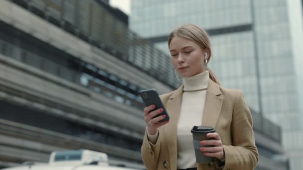 Señora de negocios con teléfono inteligente y café en la calle — Vídeos de Stock