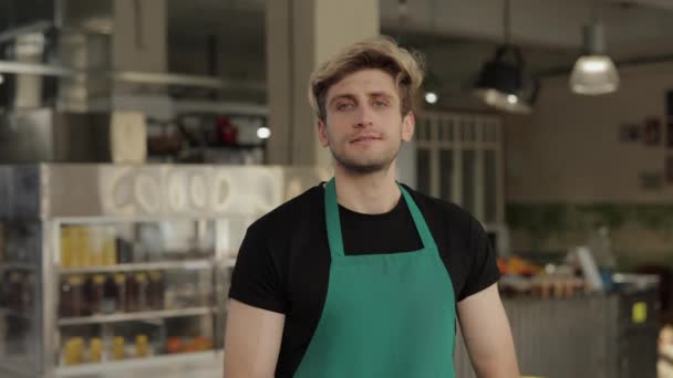 Trabajador de café positivo en delantal sonriendo y mirando a la cámara — Vídeos de Stock