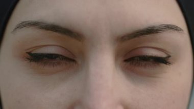 Tesettürlü kadın koyu kahverengi gözleriyle kameraya bakıyor.