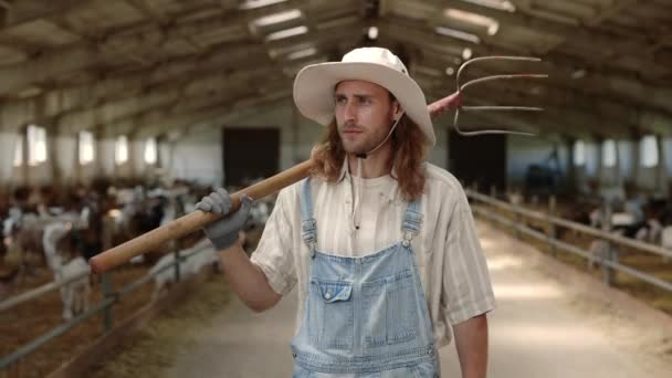 Landwirt trägt Mistgabel beim Spaziergang mit Ziegen im Stall — Stockvideo
