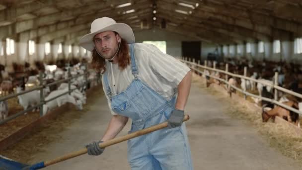 Jeune ouvrier agricole en salopette utilisant une pelle pour le nettoyage — Video