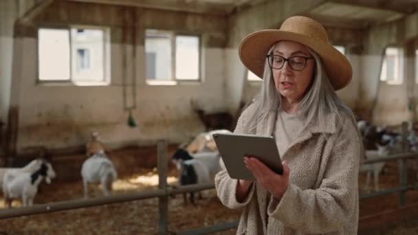Mulher mais velha bonita em chapéu de palha usando tablet no rancho — Vídeo de Stock