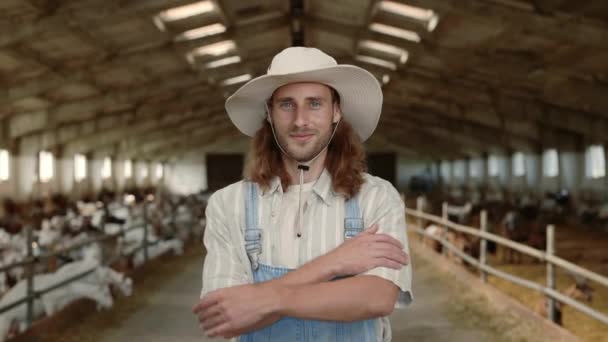 Pozytywny rolnik w mundurze stojący na ranczu z kozami — Wideo stockowe