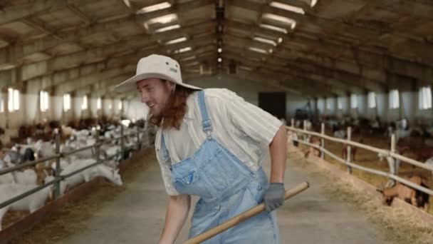 Homme souriant en uniforme nettoyage de la ferme de chèvres à l'aide d'une pelle — Video