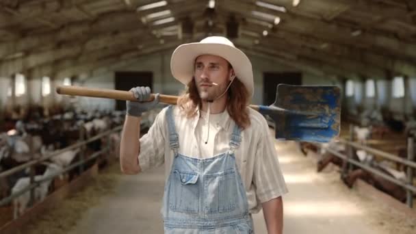 ヤギの農場を歩いている間に肩にシャベルを持っている男 — ストック動画