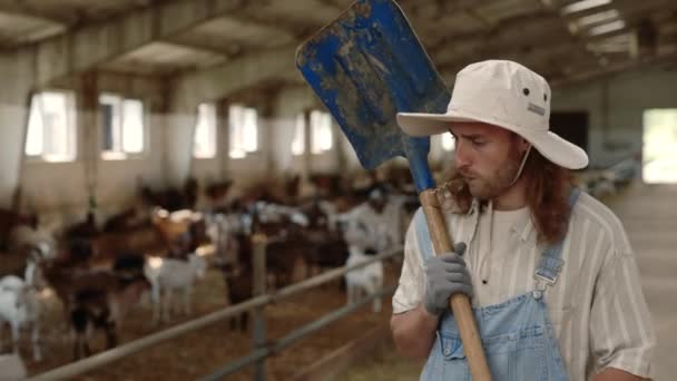 Trabalhador agrícola usando pá para limpeza rancho com cabras — Vídeo de Stock