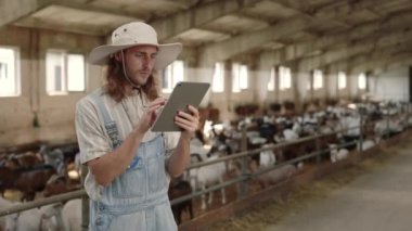 Cattleman, keçi çiftliğinde çalışmak için dijital tablet kullanıyor.