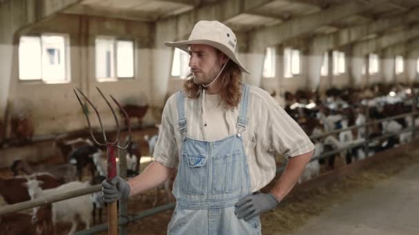 Homme positif tenant fourche tout en posant à la ferme caprine — Video